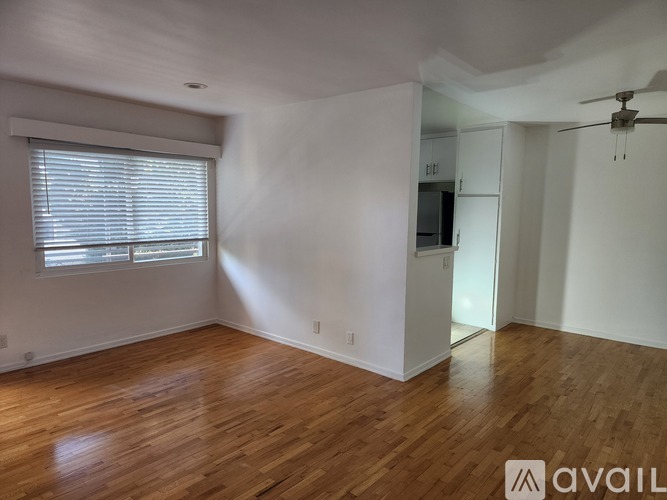 A spacious room with wooden flooring and a ceiling fan.