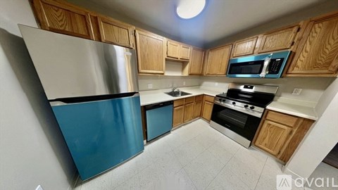 A kitchen with wooden cabinets and a blue refrigerator.
