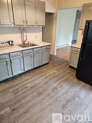 A kitchen with a black fridge and wooden floors.