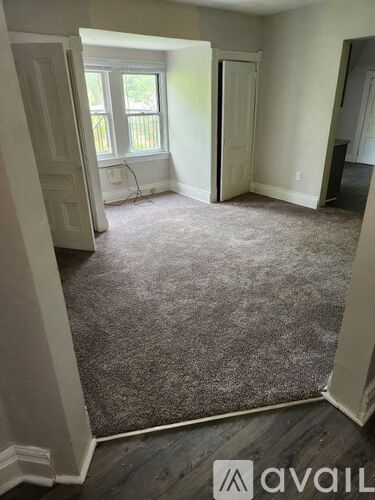 A room with a carpeted floor and a window with a view of a fence.