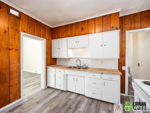 A kitchen with white cabinets and a wooden wall.