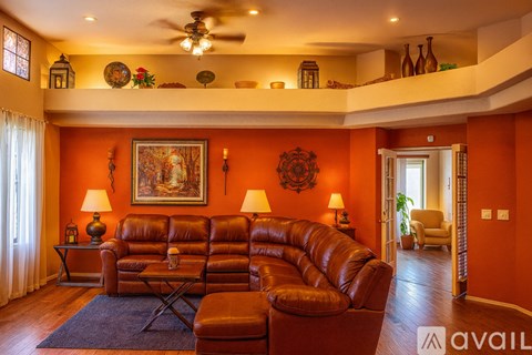 A living room with a brown leather couch and a painting on the wall.