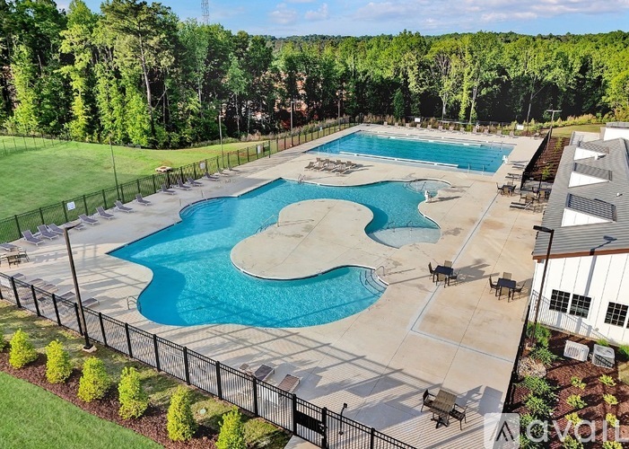 A large outdoor swimming pool surrounded by a fence and trees.