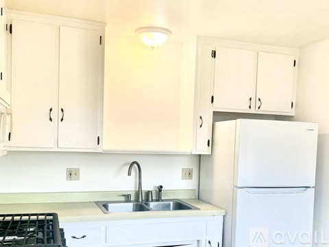 A kitchen with white cabinets and a white fridge.