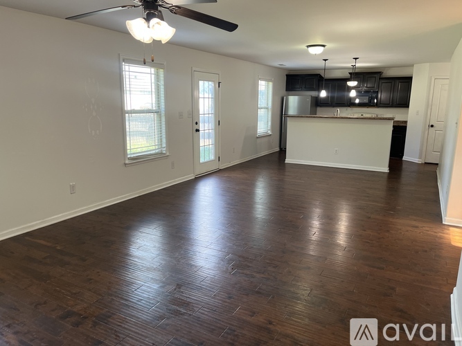 A spacious room with wooden flooring and a ceiling fan.
