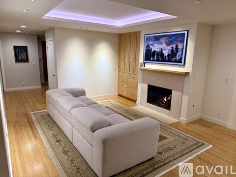 A living room with a grey sofa, a fireplace, and a painting on the wall.