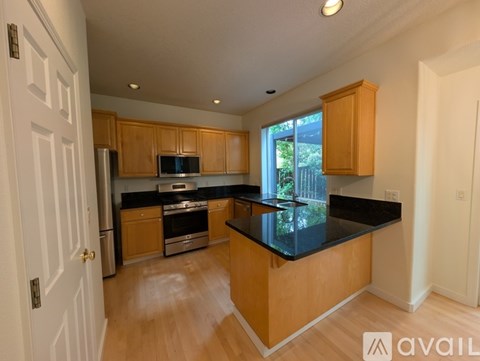 A kitchen with wooden cabinets and black countertops.