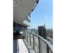 A balcony with a glass railing overlooks a cityscape.