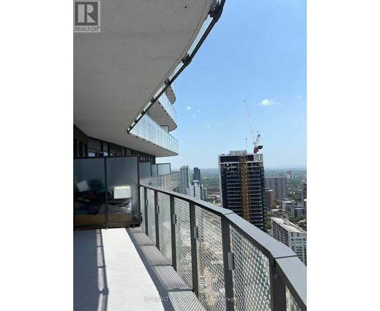 A balcony with a glass railing overlooks a cityscape.