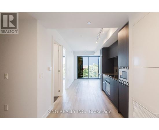 A spacious kitchen with dark cabinets and a large window.