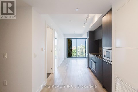 A spacious kitchen with dark cabinets and a large window.