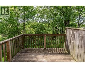 A wooden deck with a railing and trees in the background.