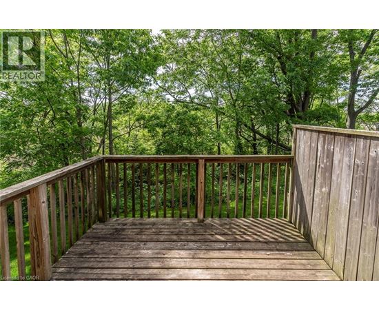 A wooden deck with a railing and trees in the background.
