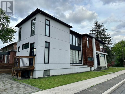 A modern two-story house with a white exterior and a balcony on the first floor.