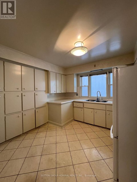 A kitchen with white cabinets and a tiled floor.