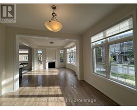 A well-lit, spacious living room with wood flooring and large windows.