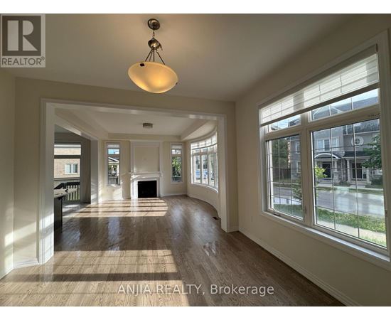 A well-lit, spacious living room with wood flooring and large windows.