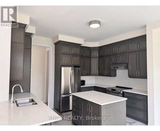 A modern kitchen with dark cabinets and stainless steel appliances.
