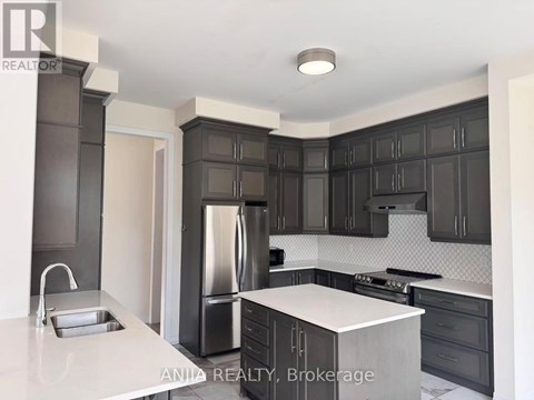 A modern kitchen with dark cabinets and stainless steel appliances.