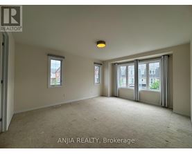 A spacious room with carpeted floor, two windows, and a door leading to another room.