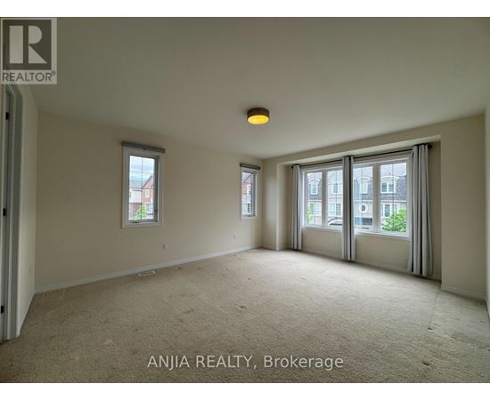 A spacious room with carpeted floor, two windows, and a door leading to another room.