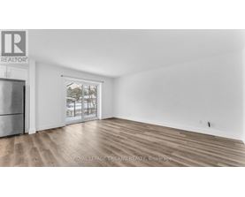 A spacious room with wooden flooring and a large window.
