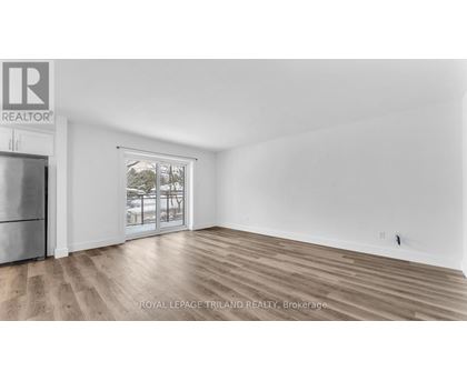 A spacious room with wooden flooring and a large window.