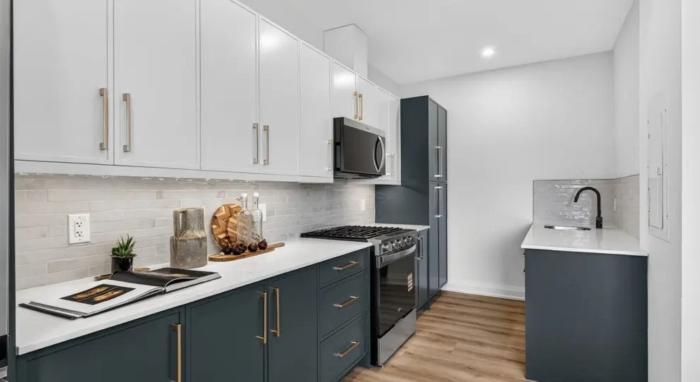 A kitchen with dark grey cabinets and white countertops.