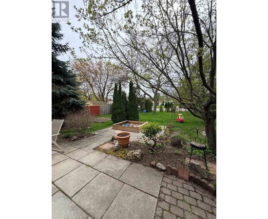 A backyard with a patio, trees, and a fire pit.