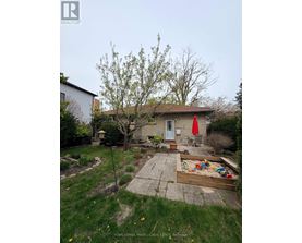 A backyard with a tree, a swing set, and a red umbrella.