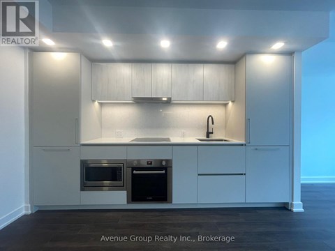 A modern kitchen with white cabinets and stainless steel appliances.