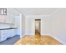 A kitchen with white cabinets and a wooden floor.