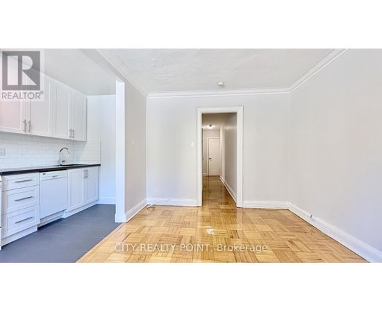 A kitchen with white cabinets and a wooden floor.