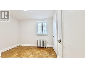 A room with a window, a radiator, and a door.