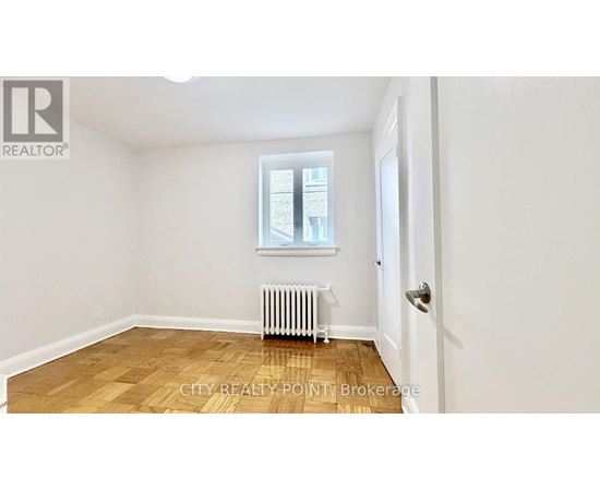 A room with a window, a radiator, and a door.