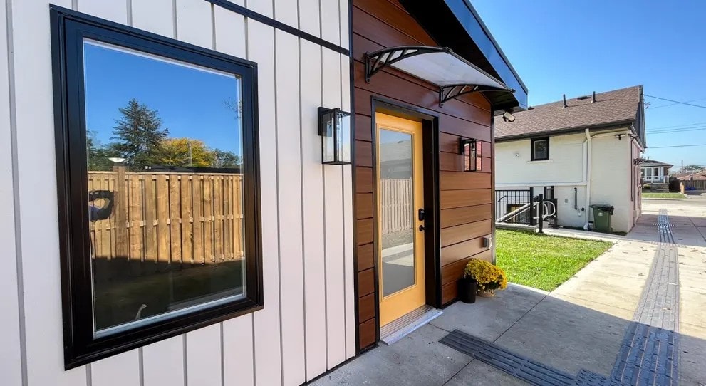 A house with a brown door and a window reflecting a wooden fence.