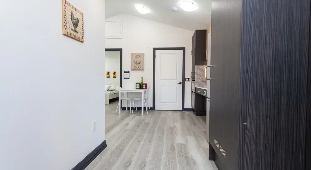 A kitchen with a white door and a white table with chairs.