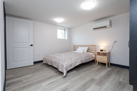 A bedroom with a bed, nightstand, and window.