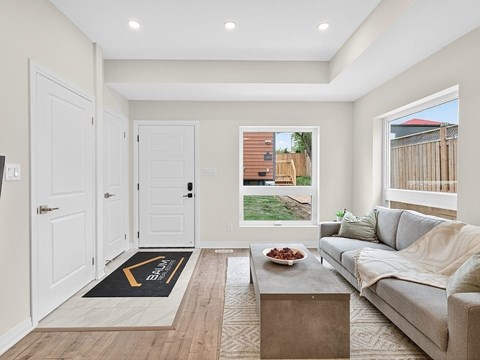 A living room with a grey couch, a coffee table, and a rug with the word "BACK" on it.