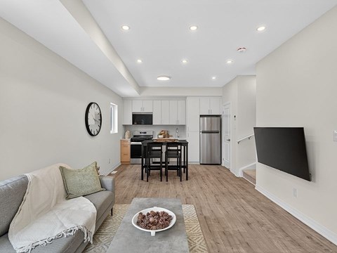 A modern living room with a grey sofa and a wooden dining table.