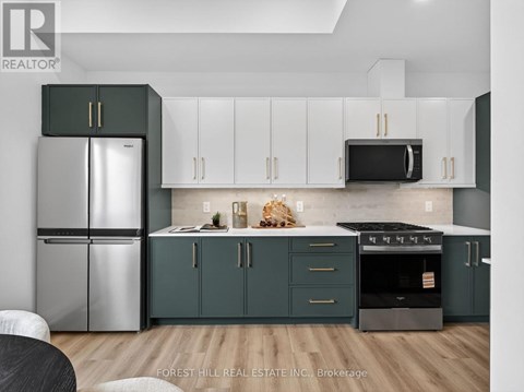 A kitchen with a refrigerator, cabinets, and a microwave.