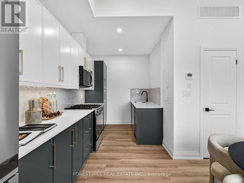 A modern kitchen with dark wood floors and white walls.