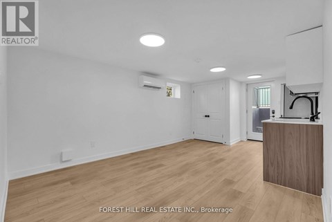 A spacious room with wooden flooring and white walls, with a reception desk on the right side.