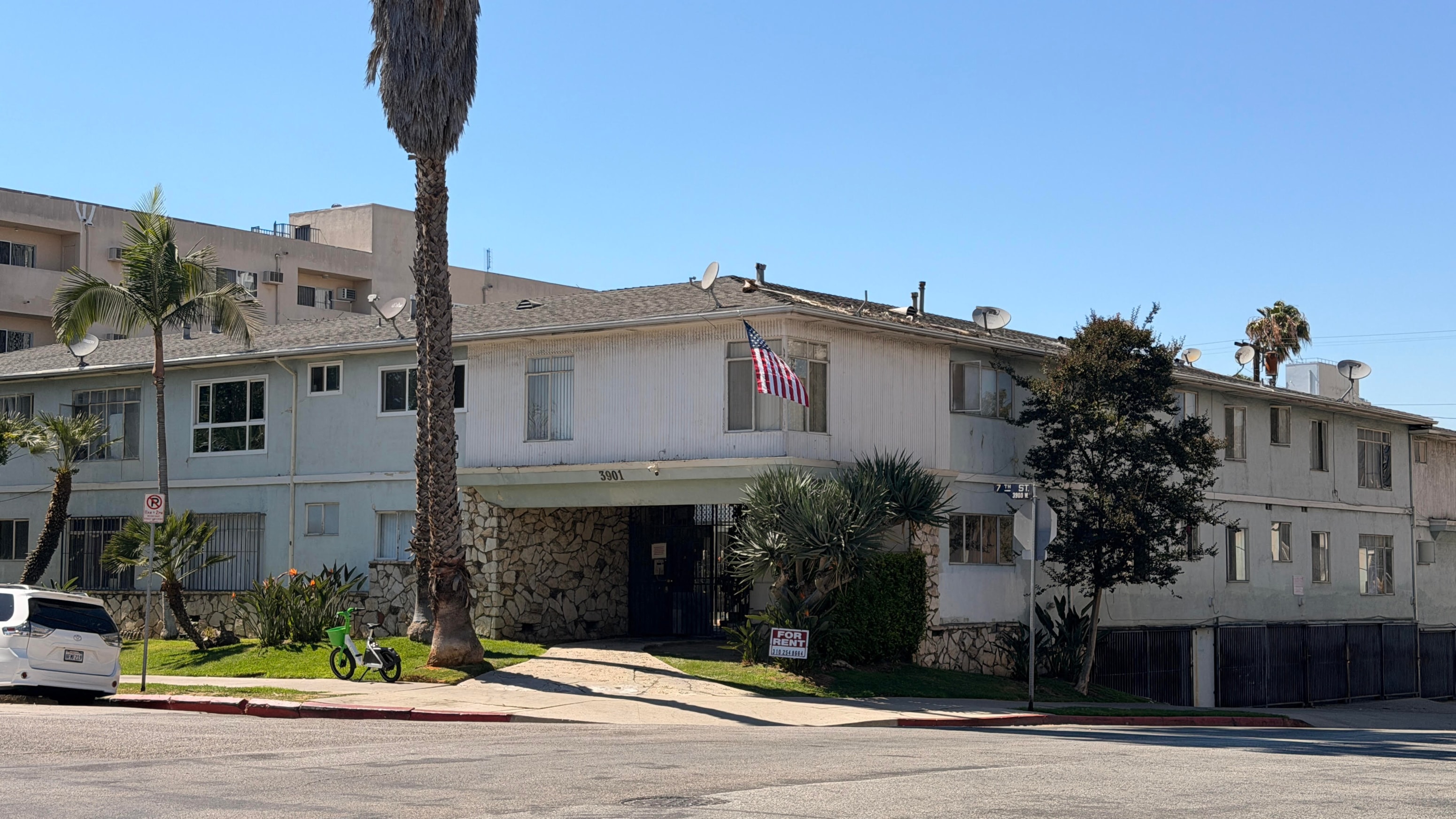 A white building with a flag on it and a tree in front.
