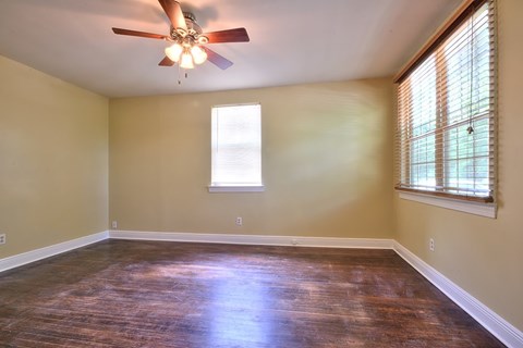 A room with a ceiling fan and wooden flooring.