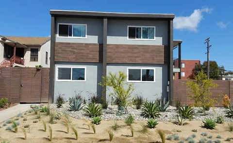 A modern house with a grey facade and a brown roof.