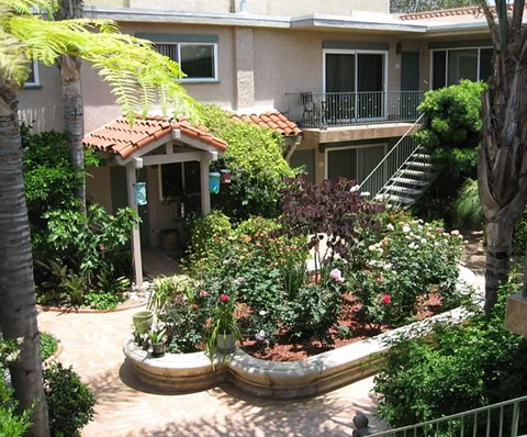 A garden with a gazebo and a staircase leading to a balcony.