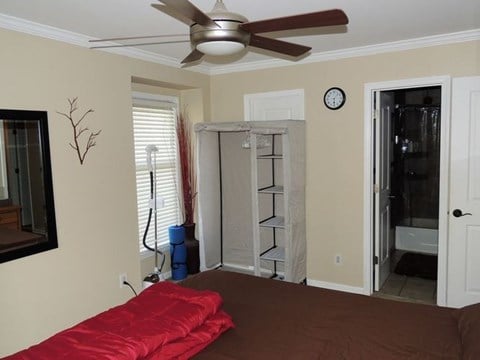 A room with a red bedspread and a ceiling fan.