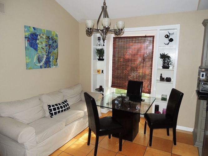 A white couch sits in a living room with a glass table and chairs.