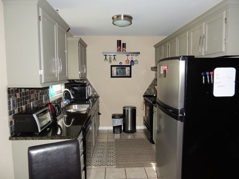A kitchen with a black fridge and a black chair.
